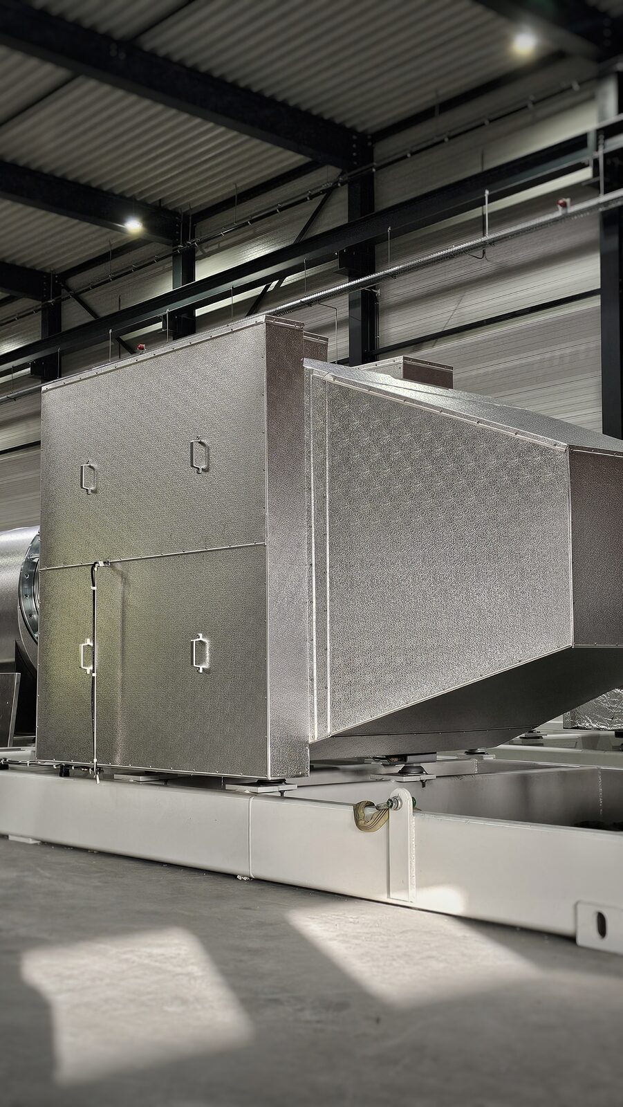 Brandwerend ommantelde uitlaatdemper van geribd aluminium plaatwerk met inspectieluiken in een bedrijfshal
