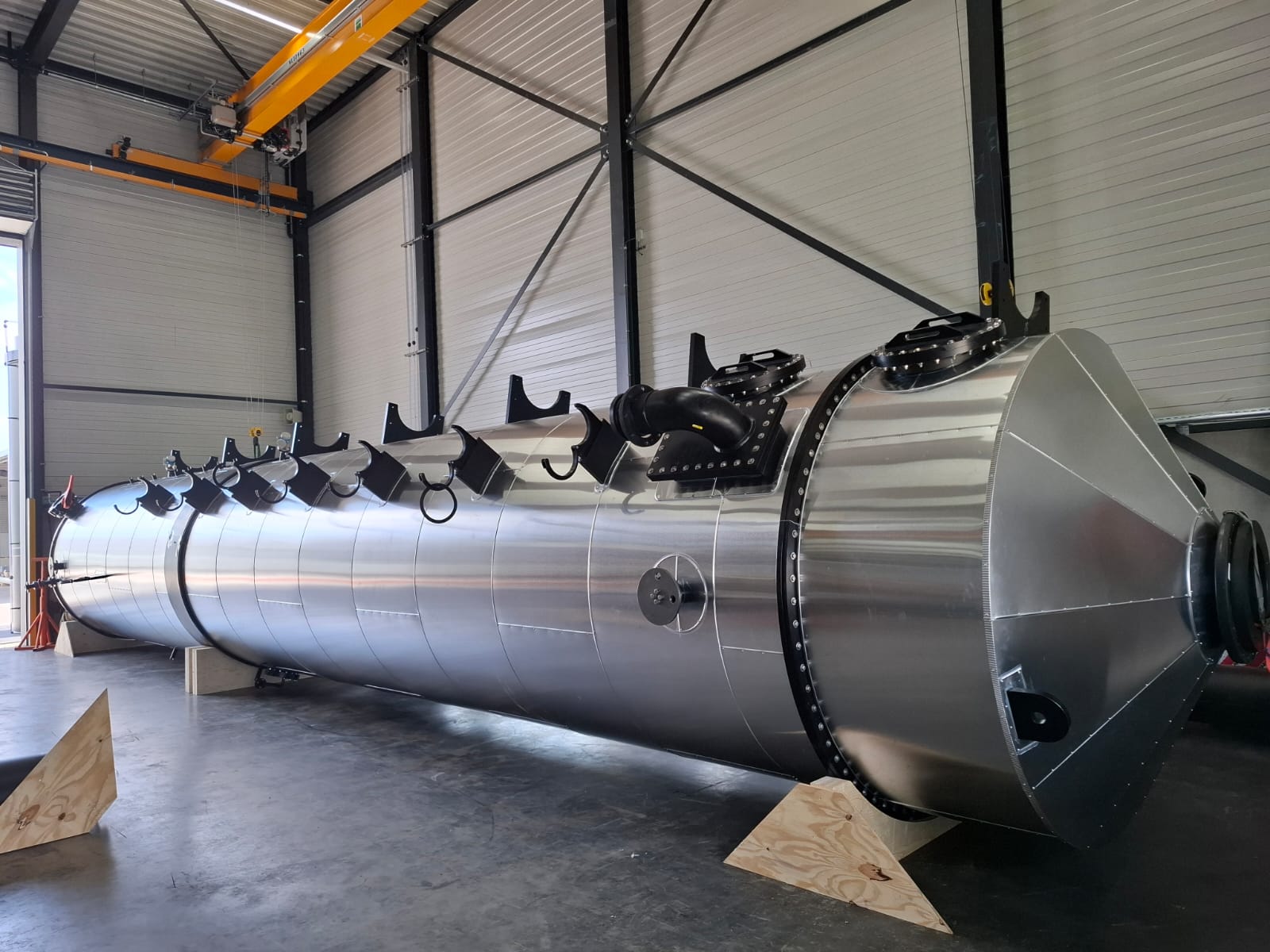 Grote liggende tank met aluminium mantel en conische kop in een productiehal