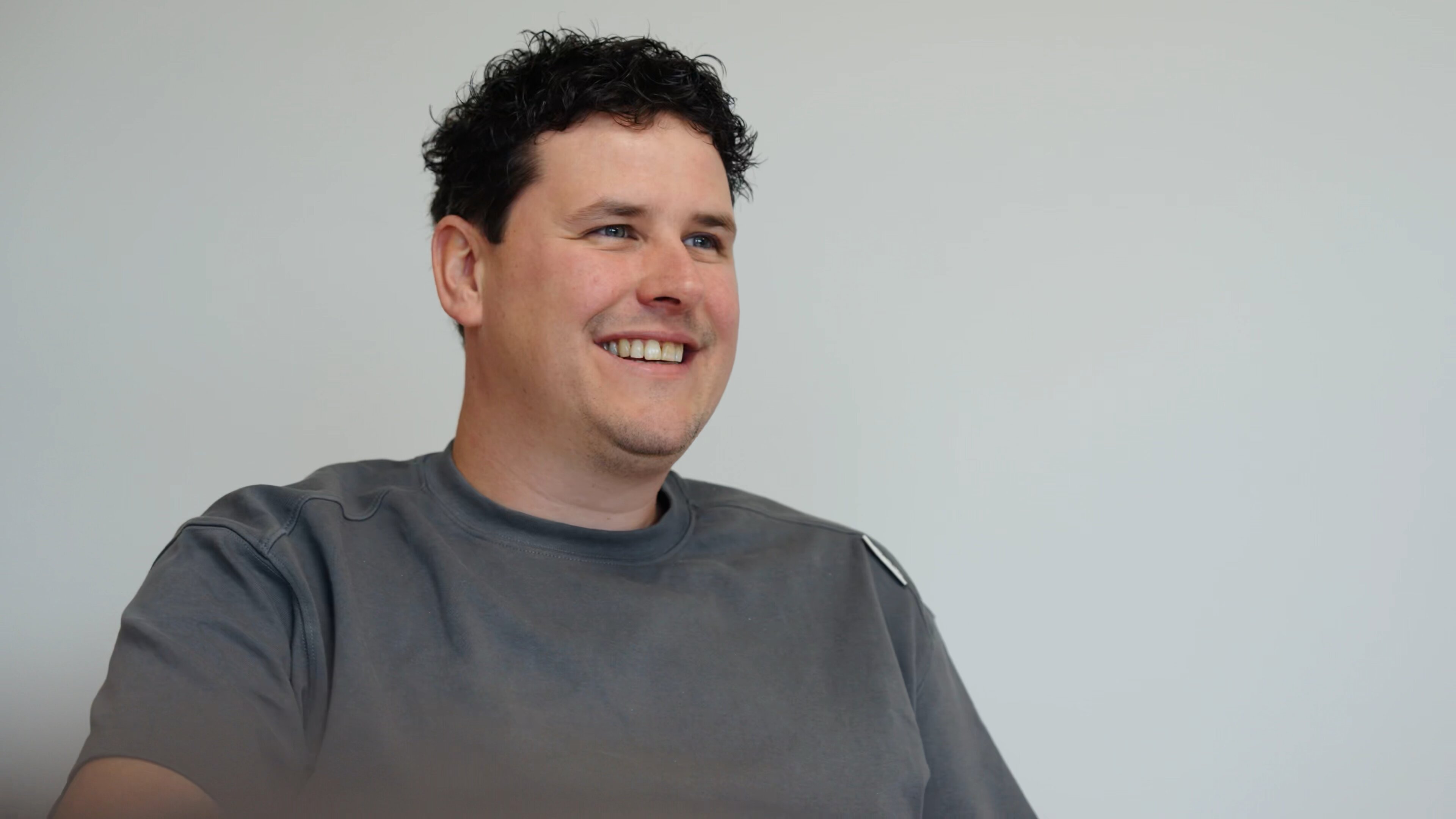 Lachende man in een grijs T-shirt tijdens een gesprek op kantoor