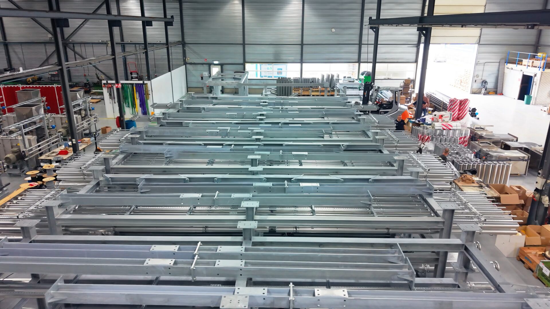 Verzinkte stalen frames met leidingbundels in de hal, met op de achtergrond een heftruck