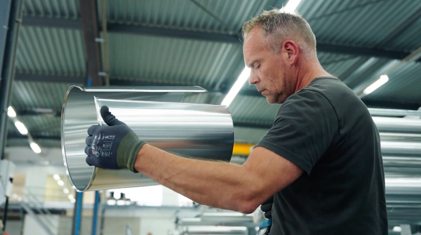 Medewerker bekijkt een ronde aluminium ommanteling in de productiehal